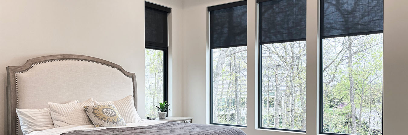 Sheer black roller shades on tall windows in a bedroom