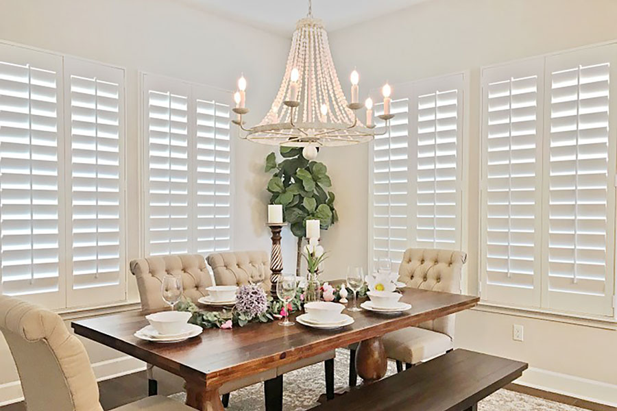White Polywood shutters in a corner of a beige dining room.