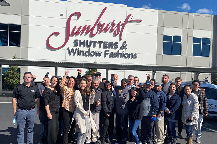 Team posing in front of Sunburst company building