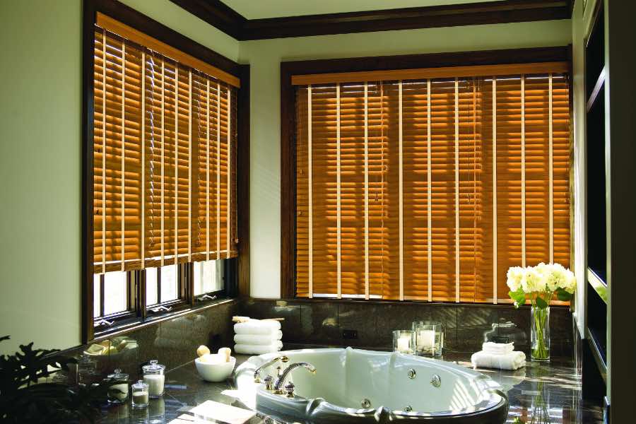 Premium quality blinds are always a stylish accent in your Las Vegas home. Brown wood blinds on large windows in a green bathroom