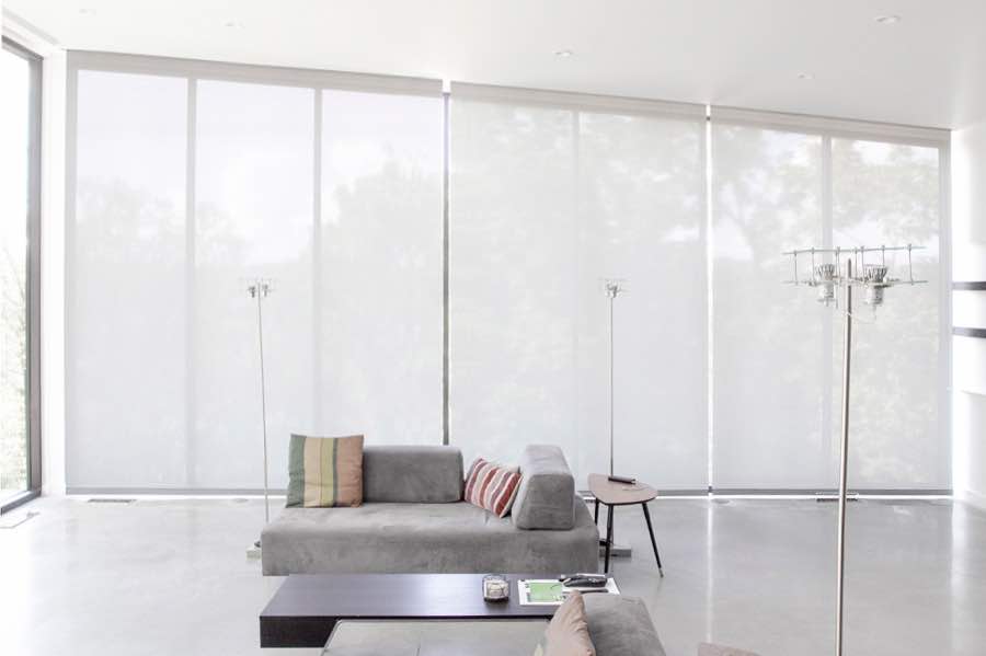 Motorized window shades make controlling natural light effortless in your Las Vegas great room. White motorized shades on a wall of tall great room windows