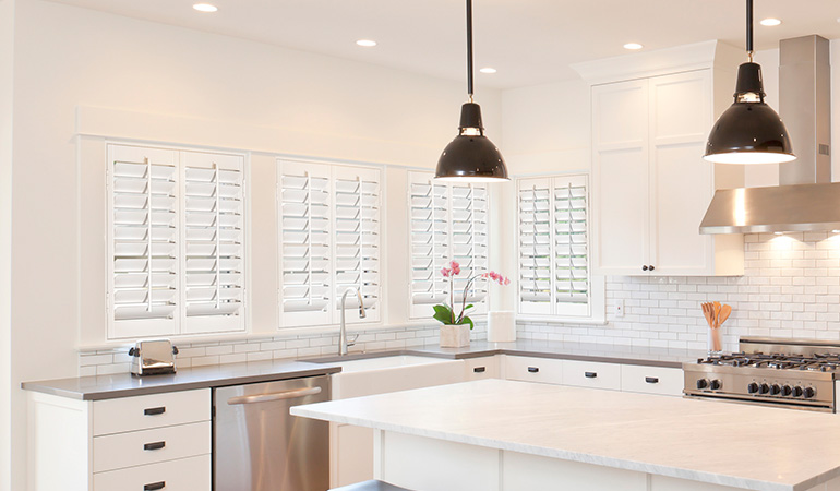 Insulate your home with crisp white Polywood shutters. White Polywood shutters in a large and modern kitchen.