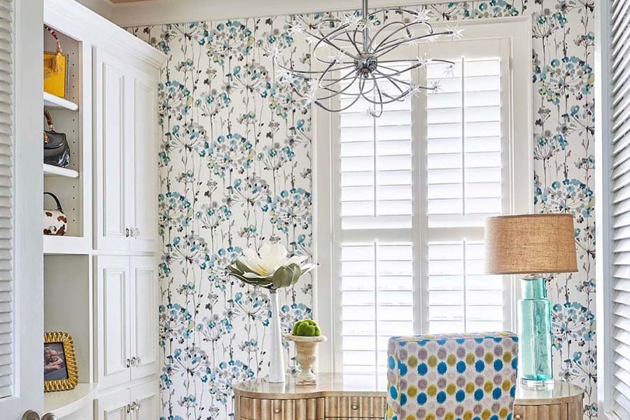 Interior shutters are a wonderful choice due to their superior light control, UV protection, and elegance. Interior shutters bringing light into a dressing area with small table and chair