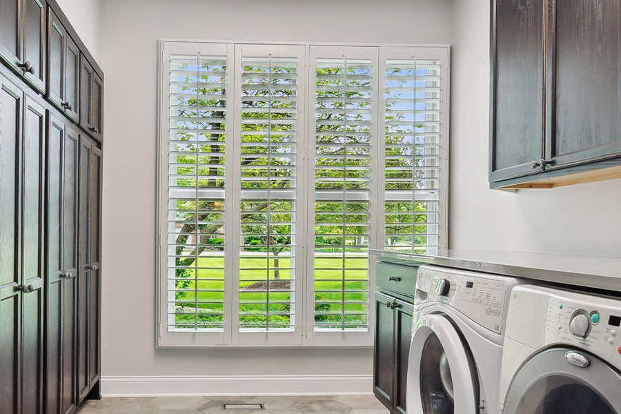 Find the perfect level of natural light for your Las Vegas laundry room with interior shutters. White Polywood shutters letting light through a laundry room window